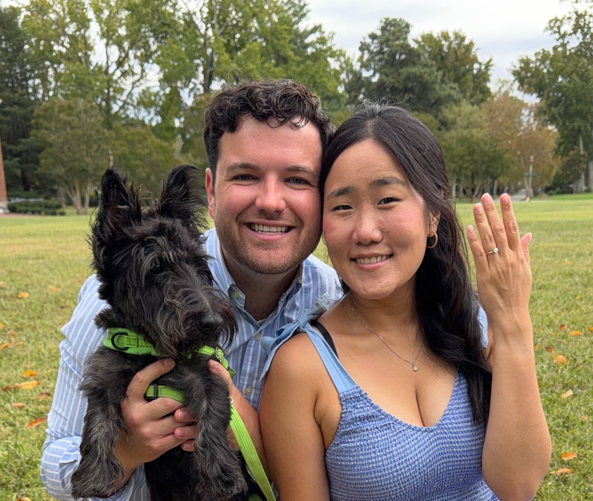 Joy and Michael smiling with their dog, the engagement ring on show