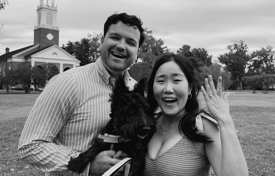 Joy and Michael laughing with their dog, showing off the engagement ring