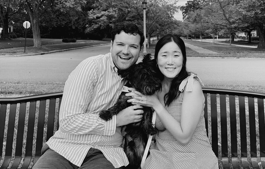Joy and Michael sitting on a park bench with their dog